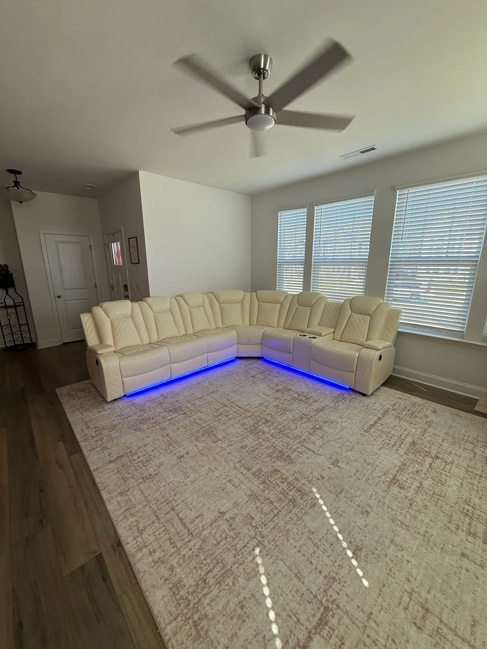 Cream L-shaped sectional sofa with blue lighting along its base in a living room