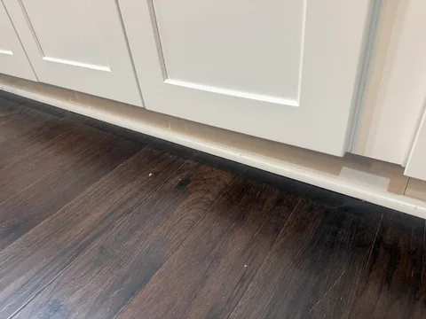 Repaired kitchen floor section along the white cabinet base