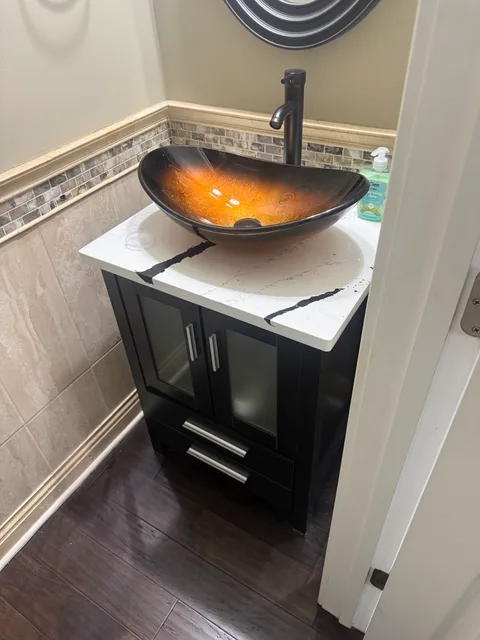 New black bathroom vanity with a white countertop and amber vessel sink installed by FixCraft VP