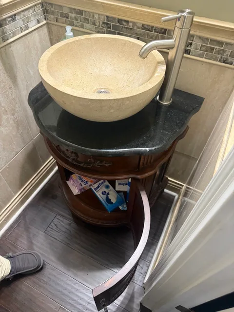 Old brown bathroom vanity with a round beige vessel sink before replacement
