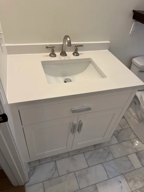 Installed white bathroom vanity with a white countertop, rectangular sink and chrome faucet