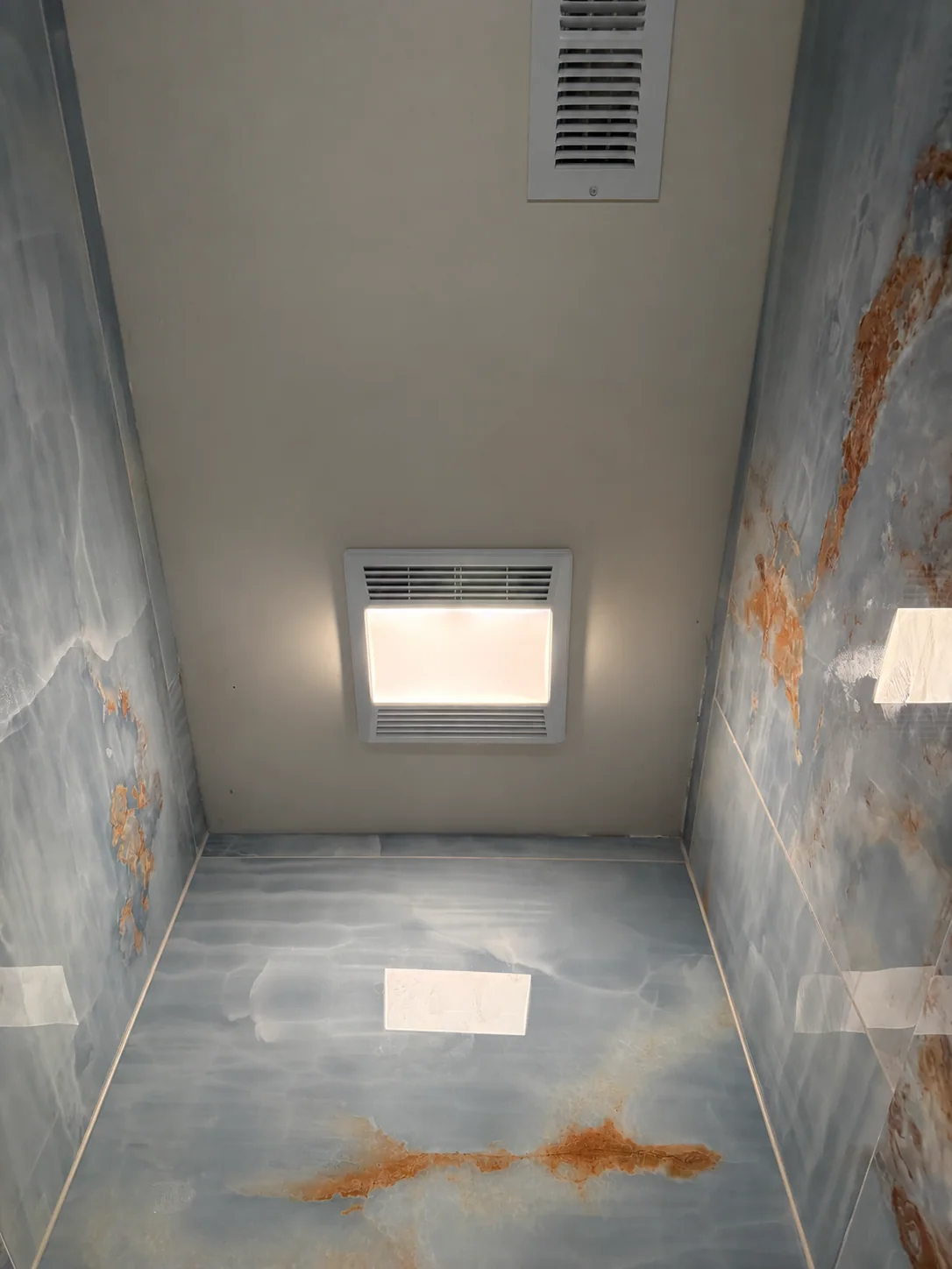 New ceiling exhaust fan with integrated light switched on in a tiled bathroom