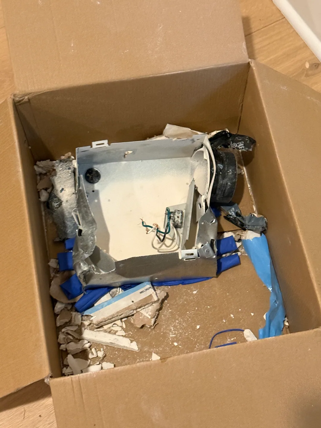 Removed old bathroom exhaust fan housing in a cardboard box after replacement