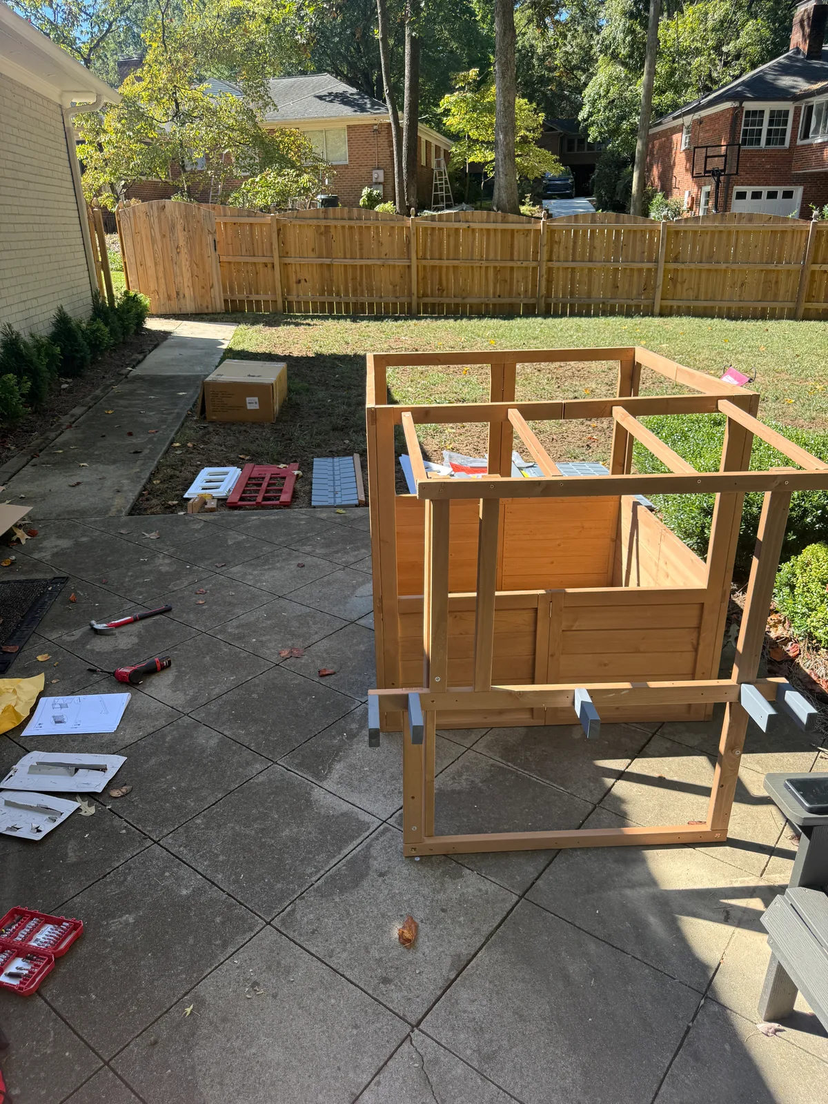 Wooden playhouse walls and canopy frame during assembly, before the roof and covers are fitted